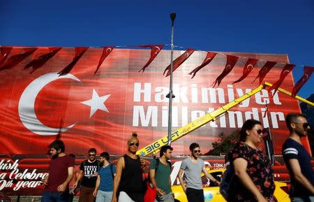 People walk past by the Ataturk Cultural Center which is covered with a huge banner at Taksim square in Istanbul, Turkey, July 22, 2016. The slogan on the banner reads that: "Sovereignty belongs to the nation". REUTERS/Osman Orsal