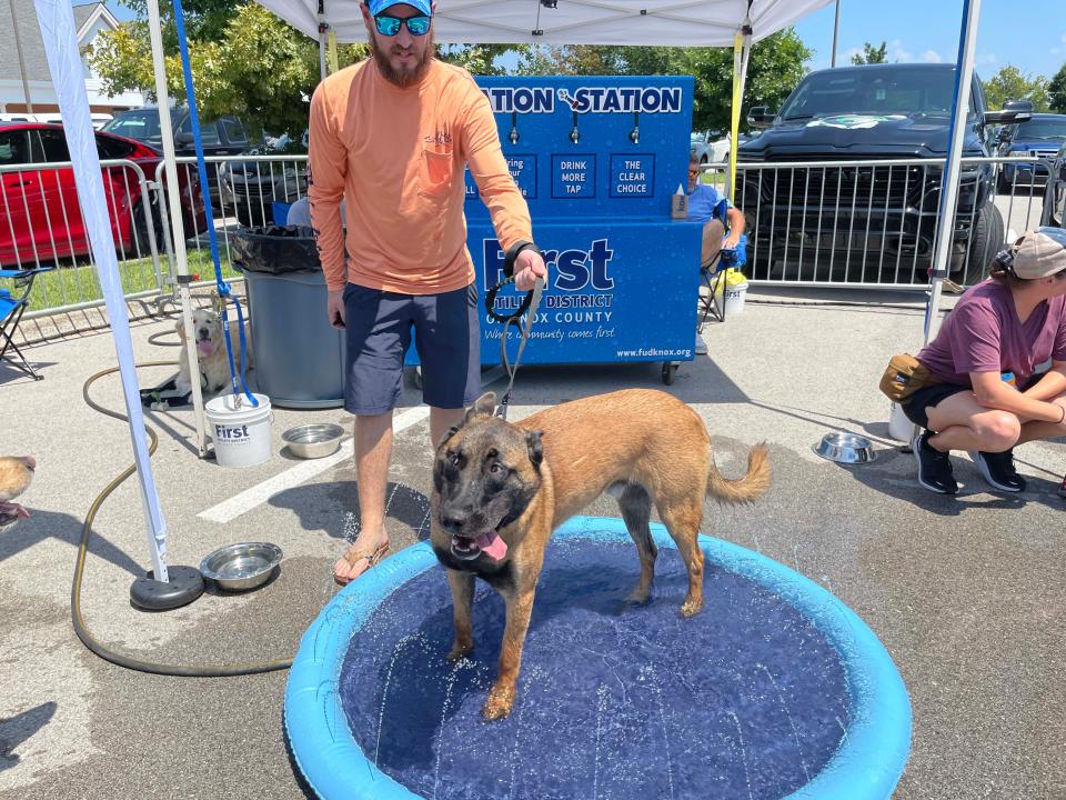 Jaren Weir cools off his dog Axle’s paws at the splash pad at Dog Daze VI held at Village Green Shopping Center in Farragut Saturday, Aug. 13, 2022.