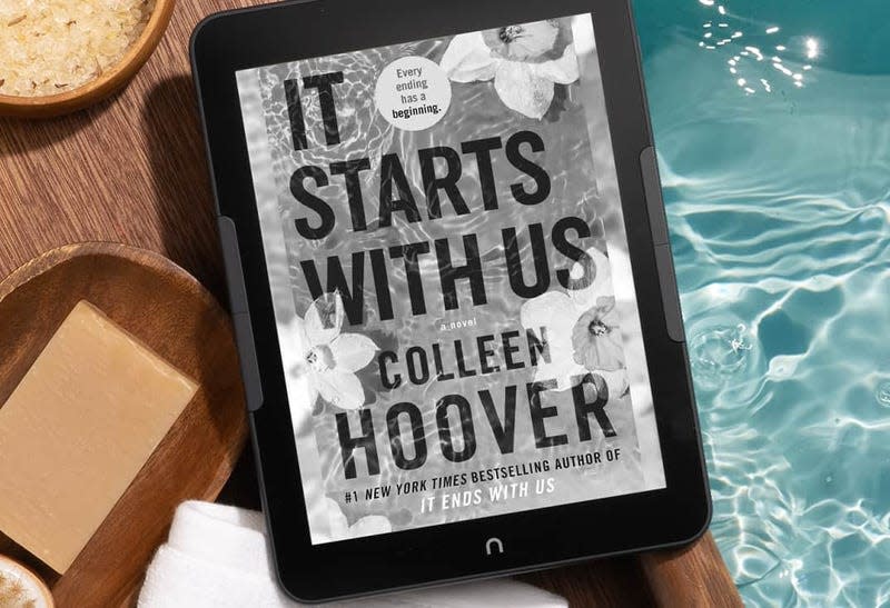 The Barnes & Noble Nook GlowLight 4 Plus sitting on a wooden table overhanging a pool.