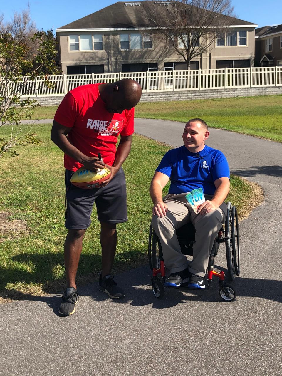 Former Tampa Bay Buccaneers Super Bowl MVP Dexter Jackson of Quincy autographs a football for injured veteran and wounded warrior Mike Delancey Monday afternoon in Pinellas Park, Florida.