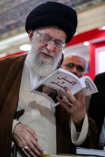 A handout picture provided by the office of Iran's Supreme Leader Ayatollah Ali Khamenei on May 11, 2018 shows him reading a translation of the "Fire and Fury" by Michael Wolff at book fair in Tehran
