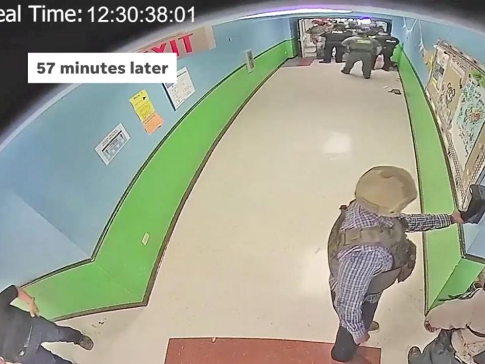 An officer is seen using a hand sanitizer dispenser roughly 57 minutes after a gunman entered Robb Elementary School in Uvalde, Texas, and killed 19 children and two teachers on 24 May, as law enforcement waited more than an hour to barge into the classroom and kill him. (Austin American Statesman/KVUE)
