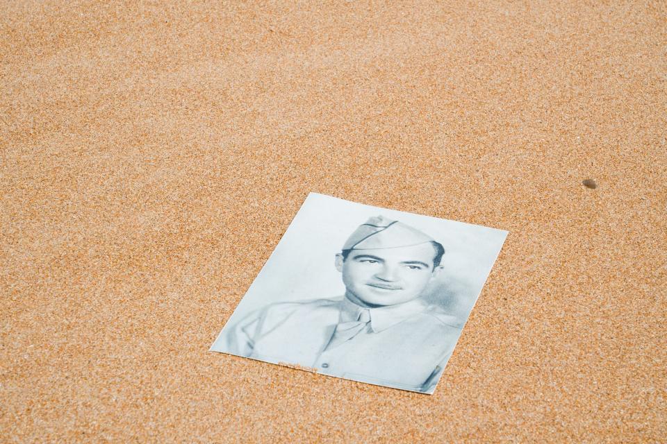 U.S. Olympic wrestler Mason Parris sets a photo of his great-grandfather, Vemont Marqua, on the sands of Omaha Beach in Normandy, France.