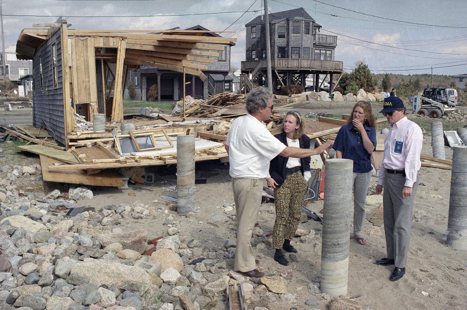 FILE— In this Sept. 25, 1991, file photo, New England regional FEMA chief Ed Thomas, right, talks with Frank and Mary Mahady, of Mattapoisett, Mass., whose home, seen intact in far background, survived Hurricane Bob because it was built to be hurricane-resistant while touring damage caused by the storm. New Englanders, bracing for their first direct hit by a hurricane in 30 years, are taking precautions as Tropical Storm Henri barrels toward the southern New England coast. (AP Photo/Stephen Rose, File)