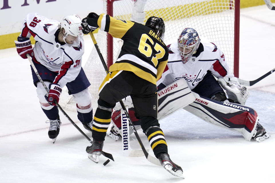 Washington Capitals' Rasmus Sandin (38) clears a rebound from in front of Capitals goaltender Darcy Kuemper (35) before Pittsburgh Penguins' Rickard Rakell can get his stick on it during the first period of an NHL hockey game in Pittsburgh, Saturday, March 25, 2023. (AP Photo/Gene J. Puskar)