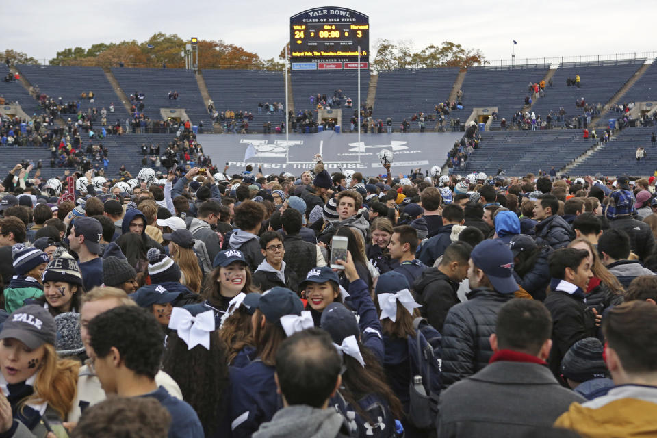 FILE - In this Nov. 18, 2017, file photo, Yale students rush the field after Yale defeated Harvard in an NCAA college football game in New Haven, Conn. There is one college football conference sitting out the reshuffling going on among its big-money brethren: The Ivy League will start the season with the same eight members it has had since it formed in 1956. (AP Photo/Gregory Payan, File)