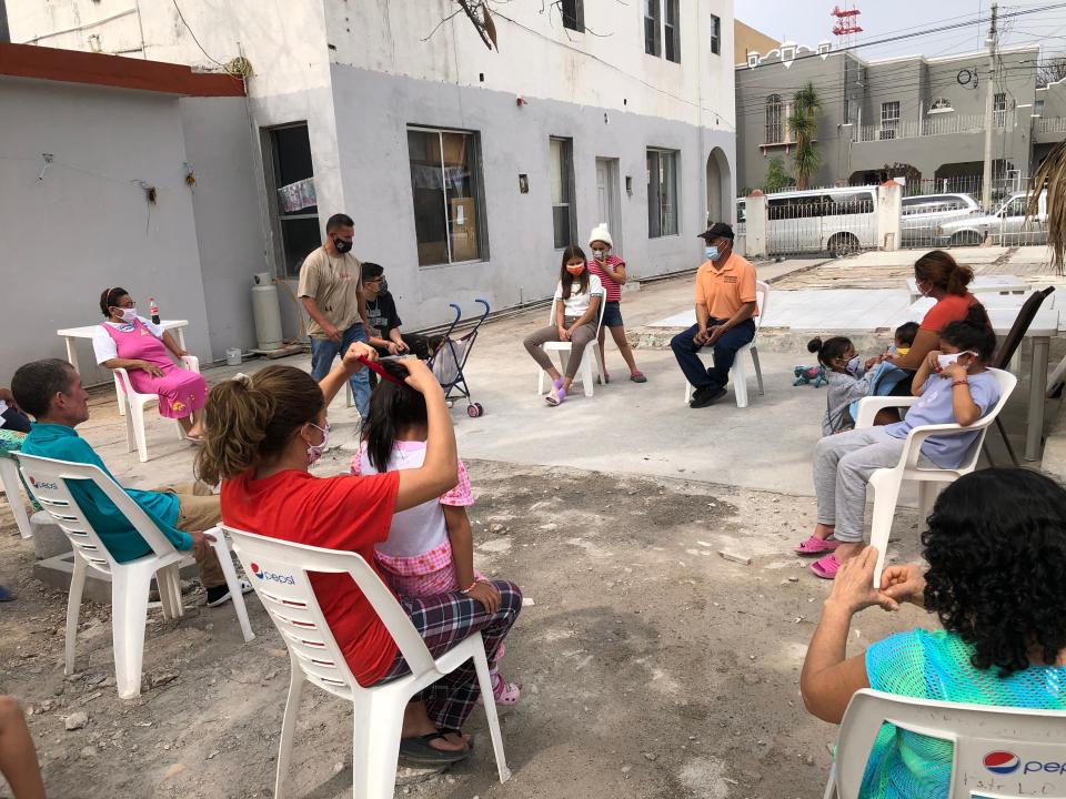 Migrants at El Buen Samaritano shelter in Nuevo Laredo, Mexico, listen to Pastor Lorenzo Ortiz share the latest news on President Joe Biden’s immigration directives.