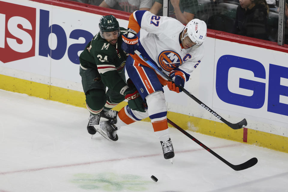New York Islanders' Anders Lee (27) and Minnesota Wild's Matt Dumba (24) go after the puck during the third period of an NHL hockey game Sunday, Nov. 7, 2021, in St. Paul, Minn. (AP Photo/Stacy Bengs)