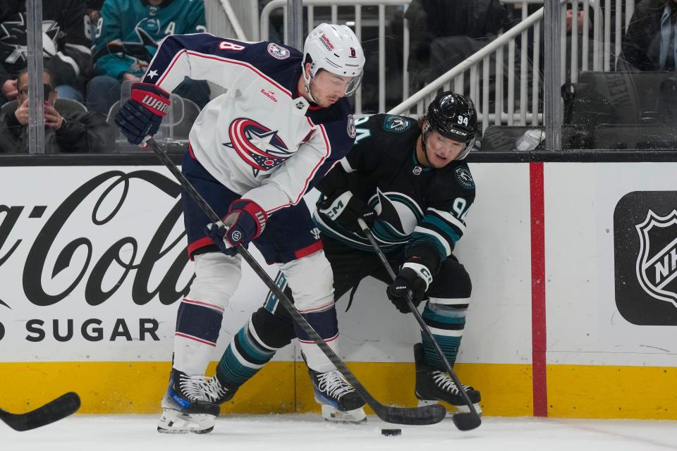 Columbus Blue Jackets defenseman Zach Werenski, left, reaches for the puck next to San Jose Sharks left wing Alexander Barabanov during the first period of an NHL hockey game in San Jose, Calif., Saturday, Feb. 17, 2024. (AP Photo/Jeff Chiu)