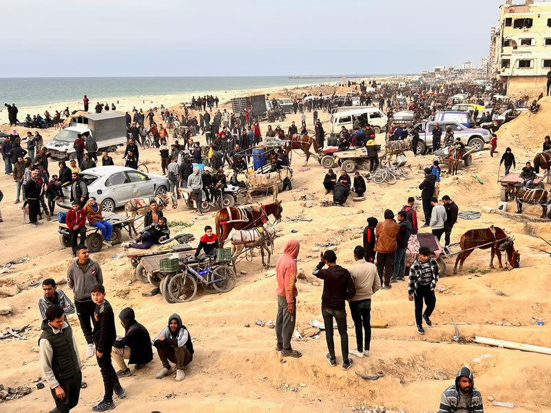 Palestinians gather as they wait for trucks carrying bags of flour to arrive, near an Israeli checkpoint, amid the ongoing conflict between Israel and Hamas, in Gaza City