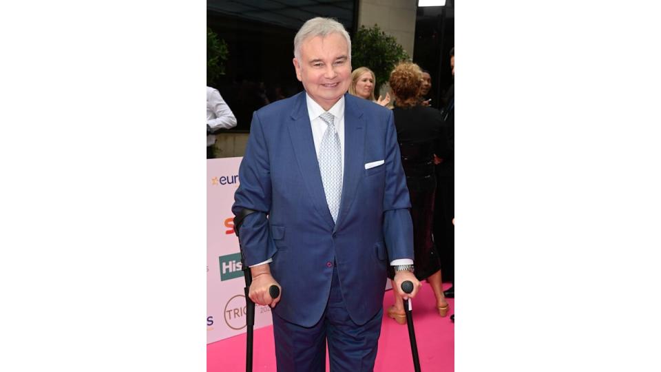 Eamonn Holmes in blue suit with crutches