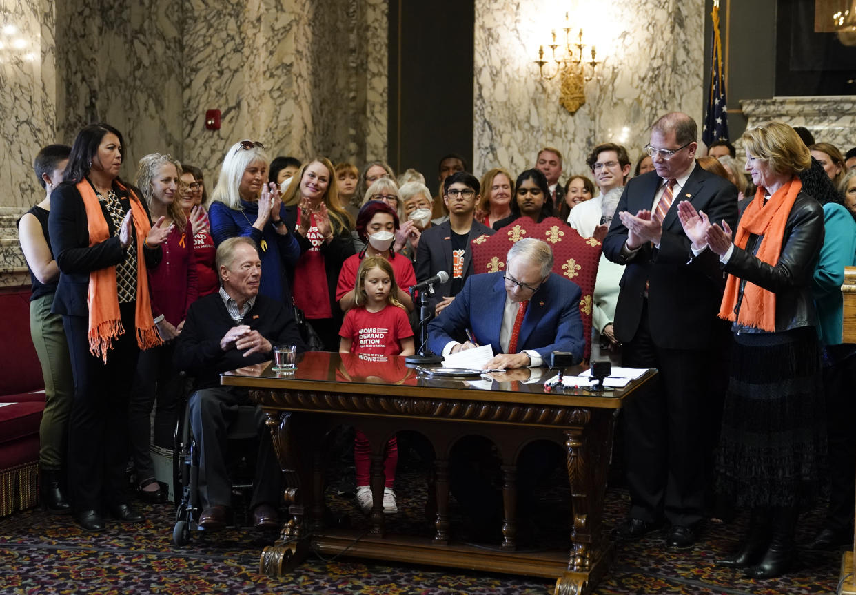 Washington Gov. Jay Inslee signs House Bill 1240, which prohibits the manufacture, importation, distribution and sale of semi-automatic assault-style weapons in the state, Tuesday, April 25, 2023, at the Capitol in Olympia, Wash., as Rep. Strom Peterson, D-Edmonds, the bill's primary sponsor, and Sen. Patty Kuderer, D-Bellevue, look on at right. (AP Photo/Lindsey Wasson)