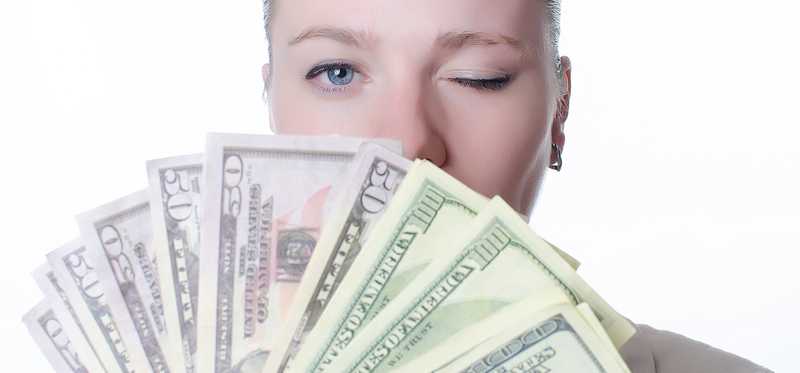 Young woman holding lots of cash and winking.