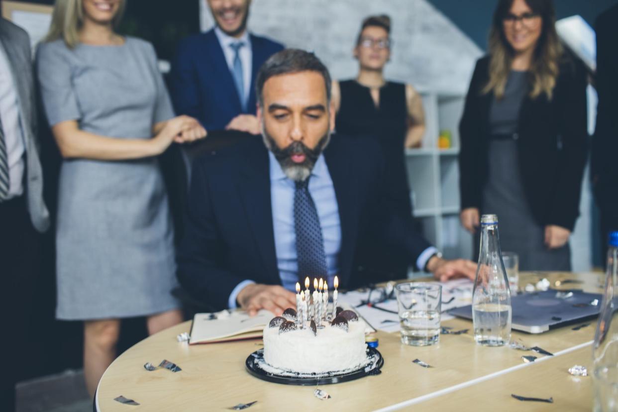 Man Blowing Birthday Candles in Office