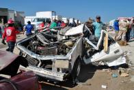 People survey a destroyed car in Ciudad Acuna, Mexico on May 25, 2015 after a tornado ripped into the town killing at least 13 people