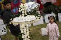 Small children run and play through the various flowers and candles at the memorial site for the victims of the Francis Scott Key Bridge collapse, Saturday, April 6, 2024, in Baltimore. (Kaitlin Newman/The Baltimore Banner via AP)