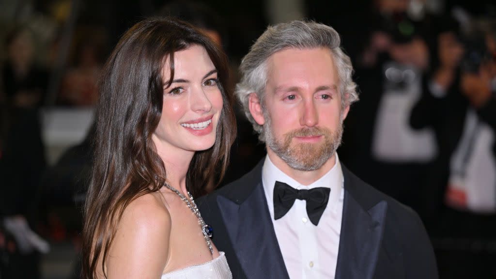 anne hathaway and her husband adam shulman posing on a red carpet together