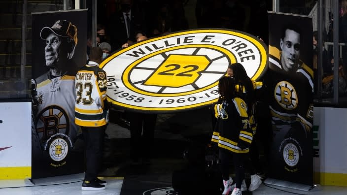 Anson Carter (left) helps carry the banner as former Boston Bruins player Willie O’Ree has his No. 22 jersey retired prior to the game between the Carolina Hurricanes and the Boston Bruins Tuesday in Boston, Massachusetts. (Photo: Rich Gagnon/Getty Images)