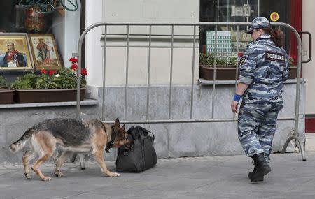 A police sniffer dog examines a suspicious bag in front of a shop in Nikolskaya street near the Kremlin that has become a popular gathering place for World Cup in Moscow, Russia July 3, 2018. REUTERS/Gleb Garanich