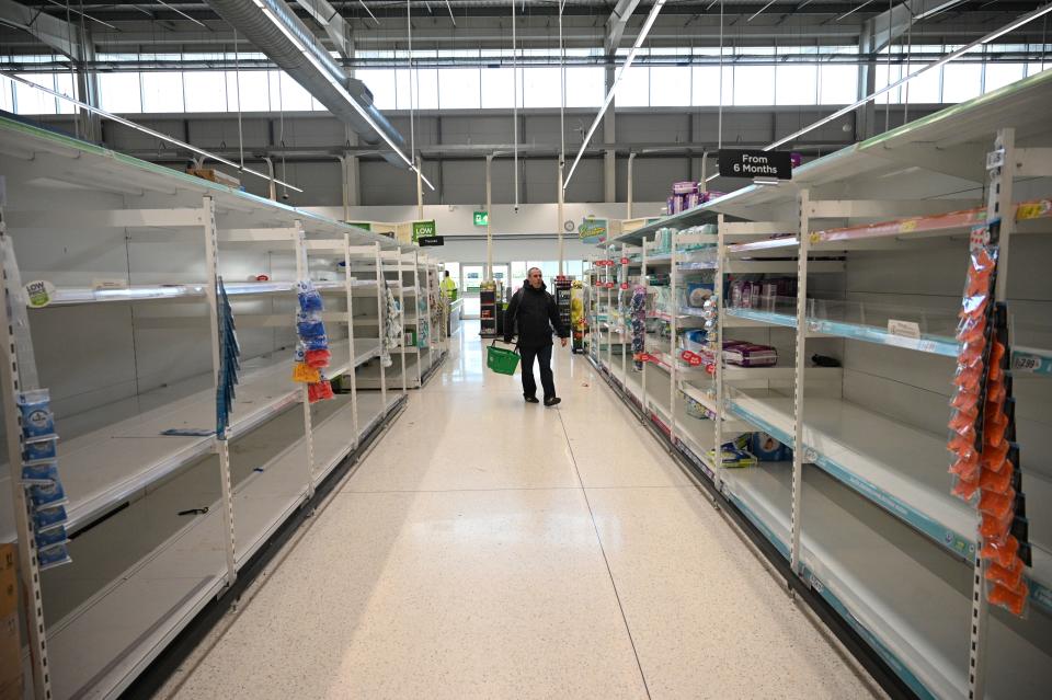A shopper walks past empty toilet roll shelves amidst the novel coronavirus COVID-19 pandemic, in Manchester, northern England on March 20, 2020. - The British prime minister urged people in his daily press conference on March 19 to be reasonable in their shopping as supermarkets emptied out of crucial items -- notably toilet roll -- across Britain. The government said it was temporarily relaxing elements of competition law to allow supermarkets to work together to maintain supplies. (Photo by Oli SCARFF / AFP) (Photo by OLI SCARFF/AFP via Getty Images)