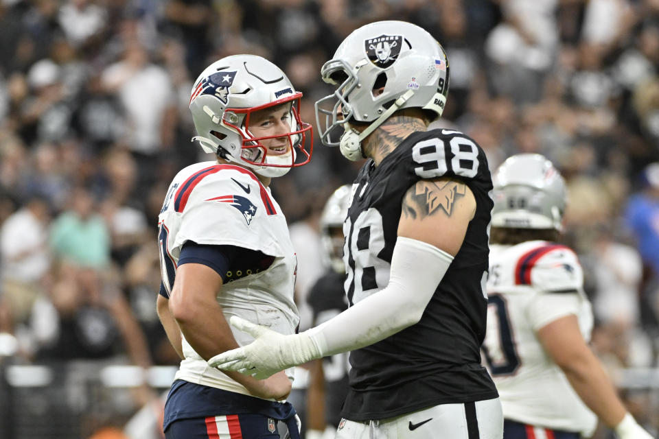 Las Vegas Raiders defensive end Maxx Crosby, right, jokes with New England Patriots quarterback Mac Jones during the first half of an NFL football game Sunday, Oct. 15, 2023, in Las Vegas. (AP Photo/David Becker)