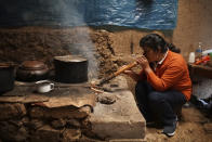 The future first lady of Peru, Lilia Paredes, 48, blows air through a hollow reed to get a fire going in her wood-burning stove in her adobe home in the rural hamlet of Chugur, Peru, Thursday, July 22, 2021. Her husband, leftist Pedro Castillo catapulted from unknown to president-elect with the support of the country's poor and rural citizens, many of whom identify with the struggles the teacher has faced. (AP Photo/Franklin Briceno)