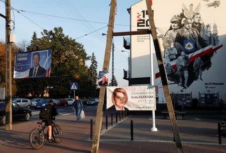 FILE PHOTO: A man rides a bicycle alongside campaign posters in Rzadzymin, Poland October 18, 2018. REUTERS/Kacper Pempel/File Photo