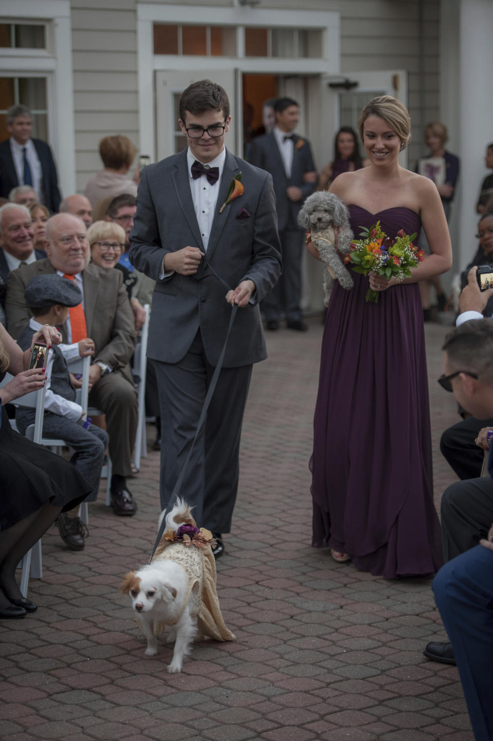 This Oct. 27, 2017 photo shows Ryan Curry and Laura Moylan walking Izzy, right, and Zoey down the aisle during the wedding of Kelly Curry and Patrick St. Onge in Haddam, Conn. The bride and groom's dogs took part in the ceremony. It's no longer unusual for brides and grooms to include pets in their wedding photos or even in the ceremony. But it can be tough to manage that along with everything else. (Jeffrey Herget/Studio 393 via AP)