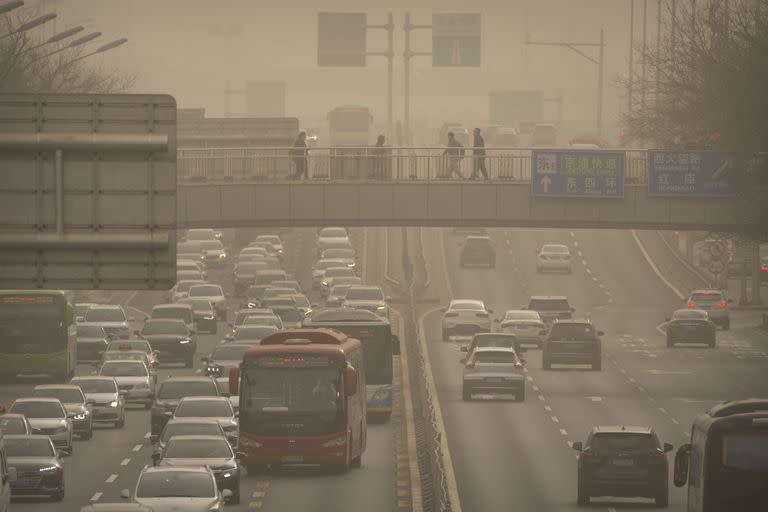 La gente camina a través de un puente peatonal en el distrito central de negocios en Beijing, el miércoles 22 de marzo de 2023.