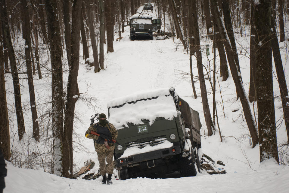 Volunteers of the Ukrainian Territorial Defense Forces inspect a damaged military vehicle in the outskirts of Kharkiv, Ukraine's second-largest city, Monday, March 7, 2022. Russia announced yet another cease-fire and a handful of humanitarian corridors to allow civilians to flee Ukraine. Previous such measures have fallen apart and Moscow’s armed forces continued to pummel some Ukrainian cities with rockets Monday. (AP Photo/Andrew Marienko).