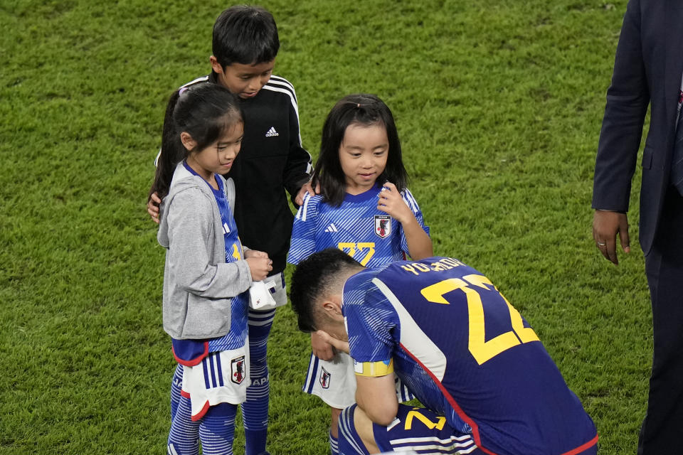 Japan's Maya Yoshida kneels in front of children after the World Cup round of 16 soccer match between Japan and Croatia at the Al Janoub Stadium in Al Wakrah, Qatar, Monday, Dec. 5, 2022. (AP Photo/Luca Bruno)