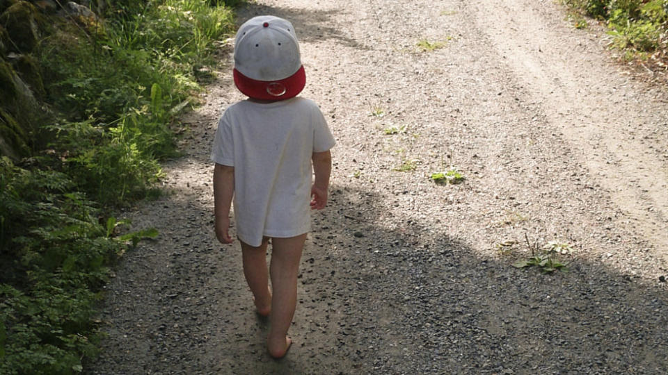 Toddler with no pants on walks along a path.