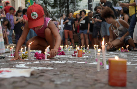 A girl lights a candle during a protest against Brazilian mining company Vale SA, in Belo Horizonte, Brazil January 31, 2019. REUTERS/Washington Alves