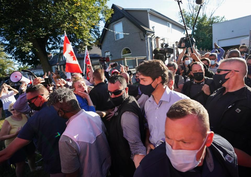 Liberal Leader Justin Trudeau is escorted by his RCMP security detail as protesters shout and throw rocks while leaving a campaign stop at a local micro brewery during the Canadian federal election campaign in London Ont., on Monday, September 6, 2021. 