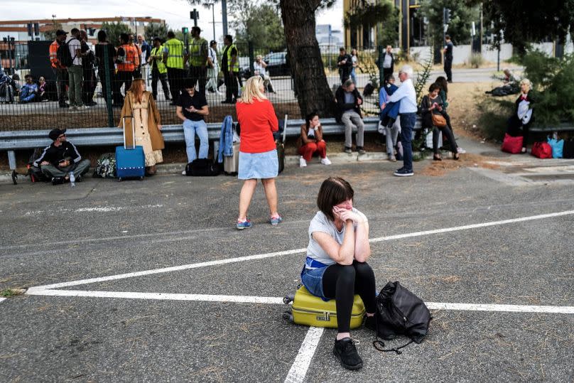 Passengers wait outside the Toulouse-Blagnac Airport in Blagnac, southwestern France, on October 18, 2023, after the airport has been evacuated.