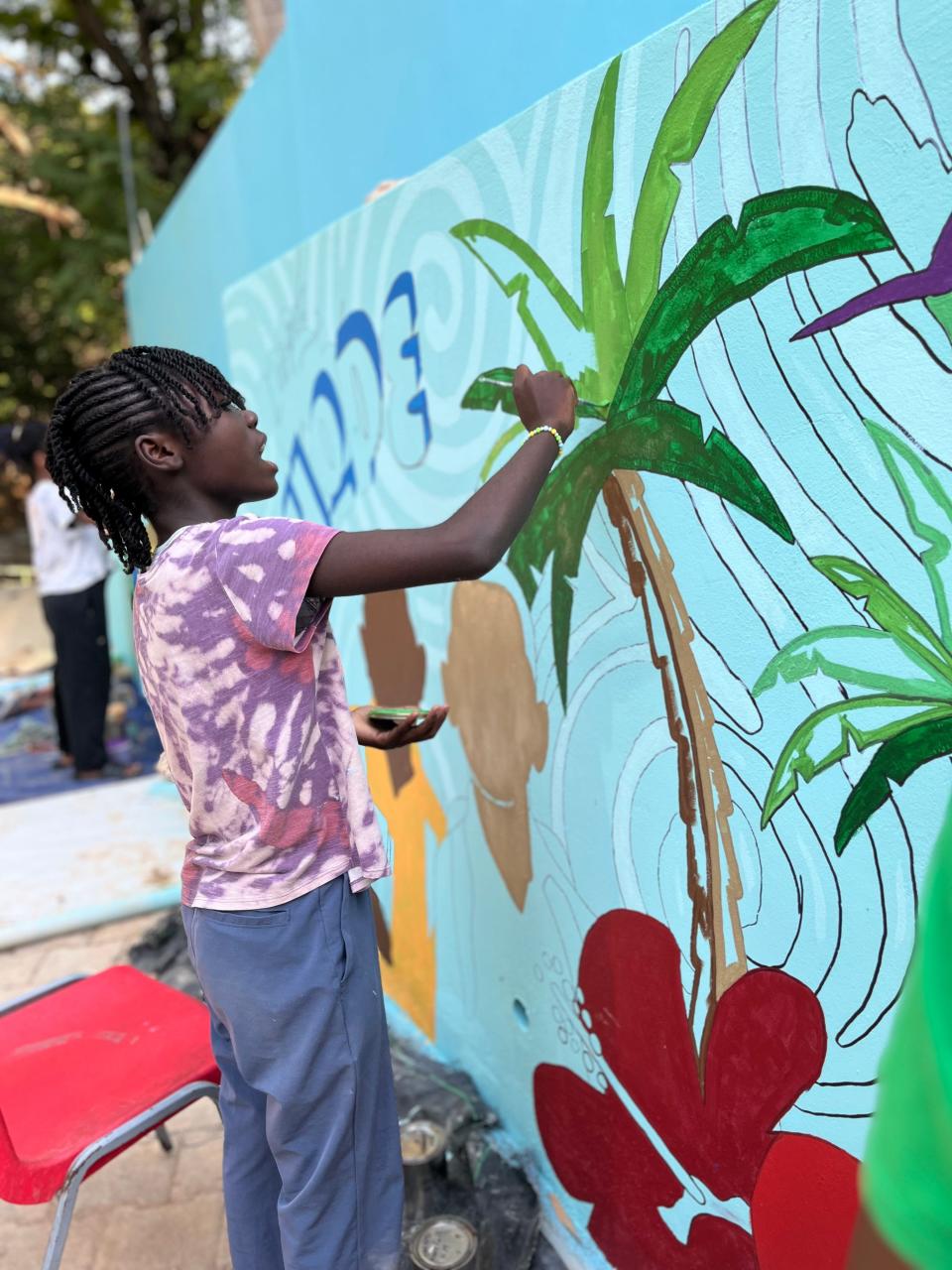 A girl paints on the mural at the Have Faith Haiti Mission & Orphanage during Mitch Albom's last visit in March 2024.