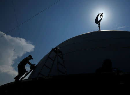 FILE PHOTO: A worker paints the top of a mosque near Lamongan in East Java province November 1, 2008. REUTERS/Beawiharta/File Photo