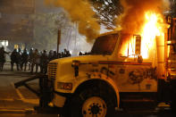 Police stand in front of a utility vehicle that was set on fire by protesters during a demonstration outside the Richmond Police Department headquarters on Grace Street in Richmond, Va., Saturday, July 25, 2020. Police deployed flash-bangs and pepper spray to disperse the crowd after the city utility vehicle was set on fire. (Joe Mahoney/Richmond Times-Dispatch via AP)