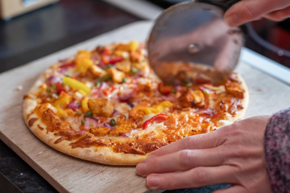 person cutting a pizza at home