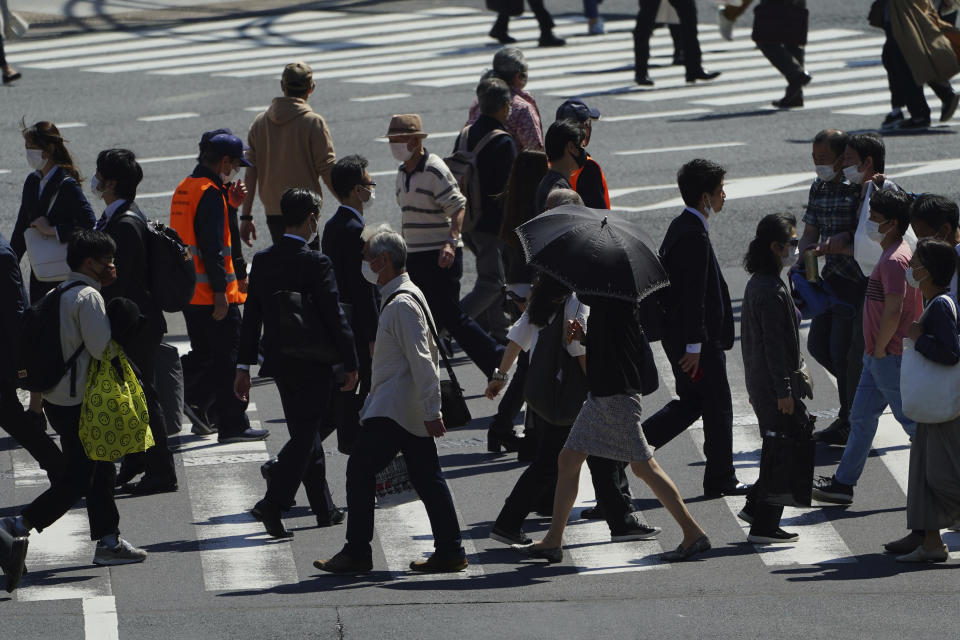 People wearing protective masks to help curb the spread of the coronavirus walk along a pedestrian crossing Wednesday, April 21, 2021, in Tokyo. The Japanese capital confirmed more than 840 new coronavirus cases on Wednesday. (AP Photo/Eugene Hoshiko)