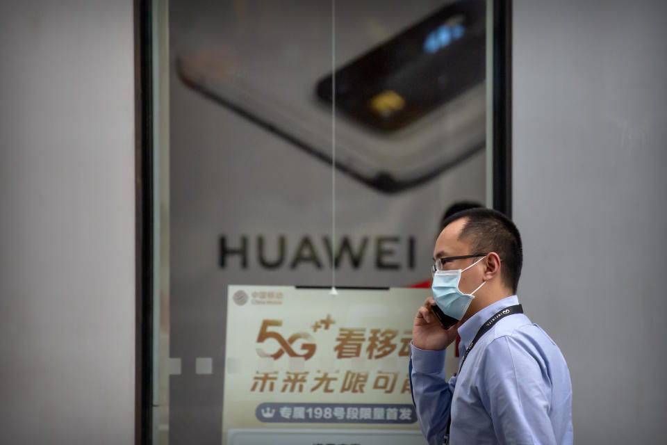 A man wearing a face mask to protect against the new coronavirus talks on his smartphone as he walks past a Huawei store in Beijing, Wednesday, July 1, 2020. China on Wednesday demanded Washington stop "oppressing Chinese companies" after U.S. regulators declared telecom equipment suppliers Huawei and ZTE to be national security threats. (AP Photo/Mark Schiefelbein)