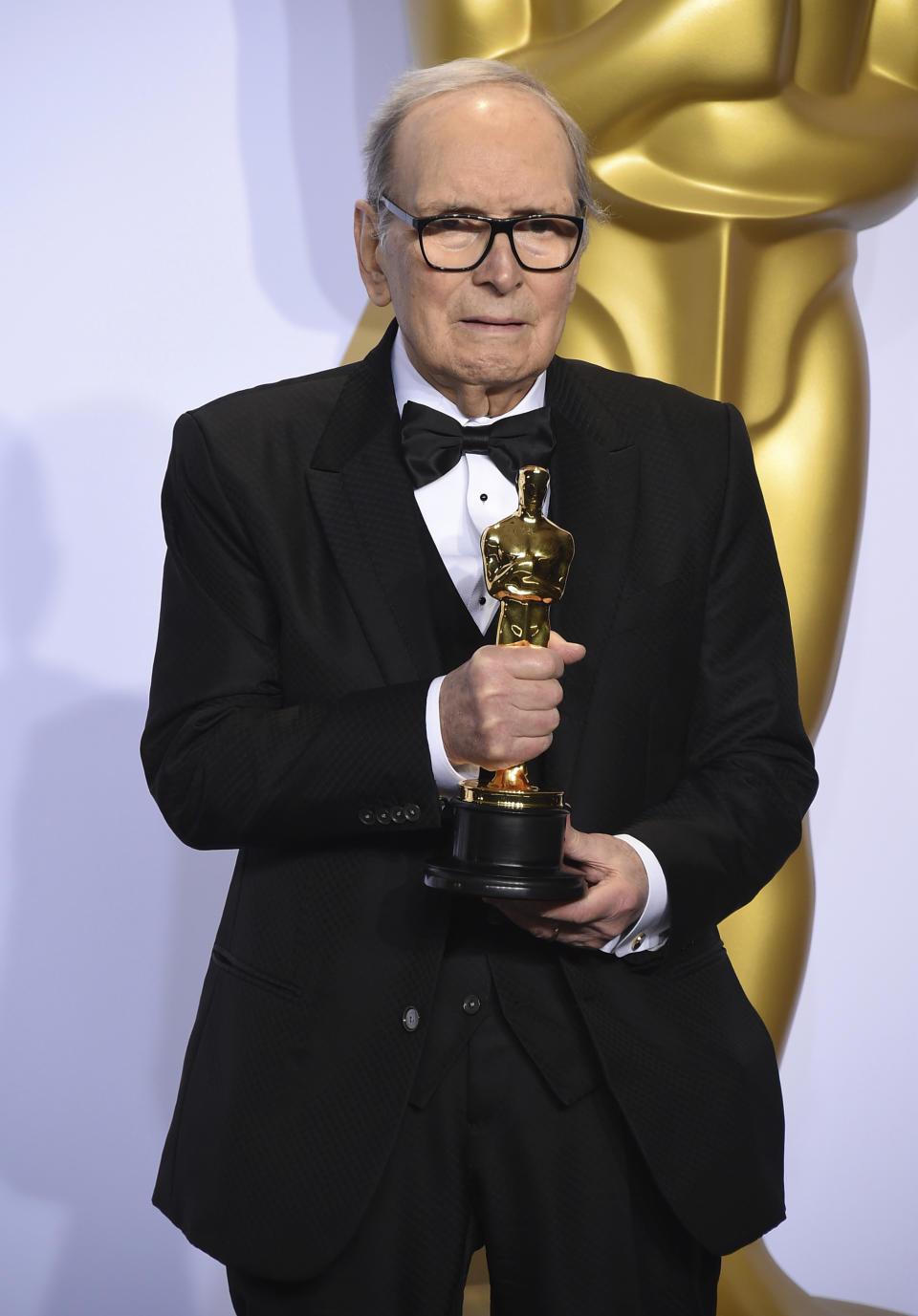 FILE - In this Sunday, Feb. 28, 2016 file photo, Italian composer Ennio Morricone poses in the press room with the award for best original score for "The Hateful Eight" at the Oscars, at the Dolby Theatre in Los Angeles. Morricone, who created the coyote-howl theme for the iconic Spaghetti Western “The Good, the Bad and the Ugly” and the soundtracks such classic Hollywood gangster movies as “The Untouchables,” died Monday, July 6, 2020 in a Rome hospital at the age of 91. (Photo by Jordan Strauss/Invision/AP, File)