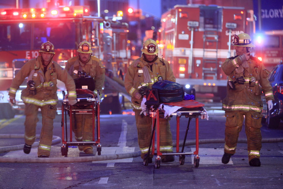 FILE - Los Angeles Fire Department firefighters push gurneys at the scene of a structure fire that injured multiple firefighters, May 16, 2020. The owner of a downtown Los Angeles building where an explosion injured 12 firefighters has been allowed to enter a judicial diversion program that allows him to avoid jail time. A court commissioner on Wednesday, March 30, 2022, granted Steve Sungho Lee's request to enter the two-year program. (AP Photo/Damian Dovarganes, File)