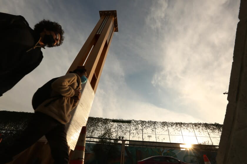 LOS ANGELES, CA - JANUARY 14, 2022 - - Pedestrians walk past one of the columns that will make up the gateway arch in Historic Filipinotown on January 14, 2022. Eliseo Art Silva is the designer of the Historic Filipinotown gateway currently being erected and will hang over Beverly Blvd. The arch is intended to act as a cultural marker to welcome people into the neighborhood. But the arch is also a symbol for people to project onto it their ideals and values of what it means to be Filipino American. Longtime community members see their own family histories reflected in the project. Others see it as a part of Filipino Americans' struggle for visibility in White America. (Genaro Molina / Los Angeles Times)