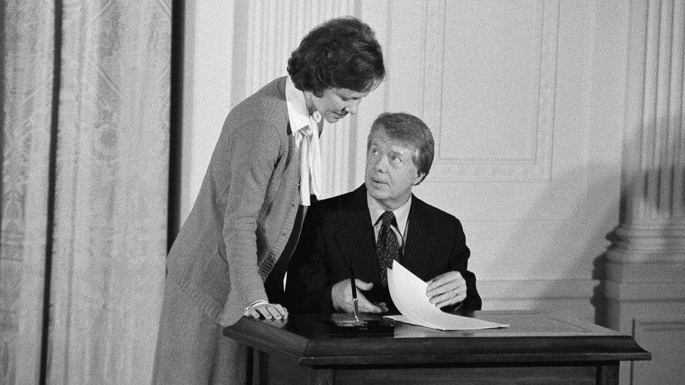 President Jimmy Carter talks with first lady Rosalynn Carter prior to signing an executive order establishing a Presidential Commission on Mental Health on February 17, 1977, in the East Room of the White House. - Charles Tasnadi/AP