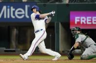 Texas Rangers' Jonah Heim follows through on a RBI single as Oakland Athletics catcher Sean Murphy looks on in the sixth inning of a baseball game in Arlington, Texas, Tuesday, Aug. 16, 2022. Adolis Garcia scored on the hit. (AP Photo/Tony Gutierrez)