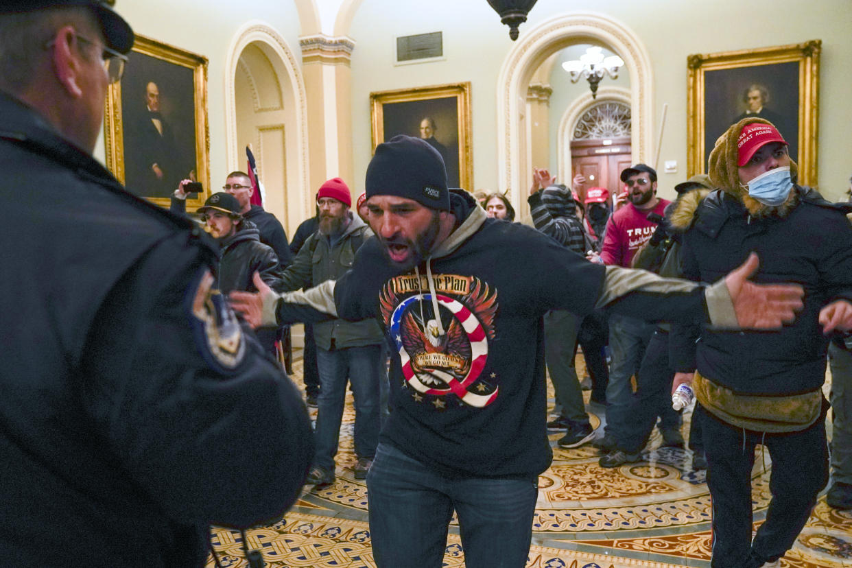 In this Wednesday, Jan. 6, 2021 file photo, Trump supporters, including Doug Jensen, center in a QAnon shirt, confront U.S. Capitol Police in the hallway outside of the Senate chamber at the Capitol in Washington. (Manuel Balce Ceneta/AP)