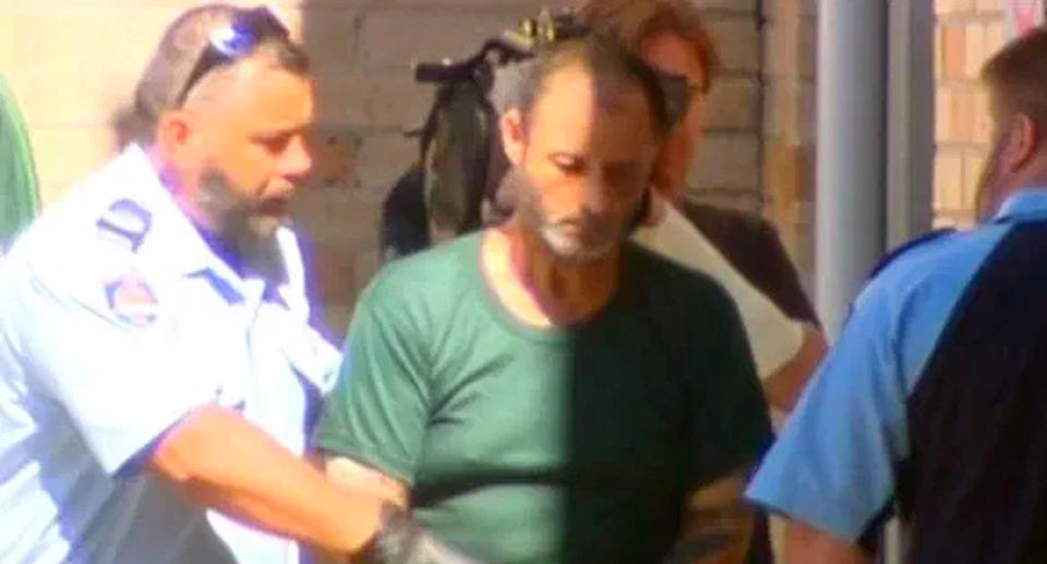 Anthony Sampieiri is pictured in a green shirt flanked by police.