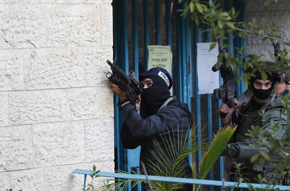 Israeli police officers hold weapons near scene of attack at a Jerusalem synagogue