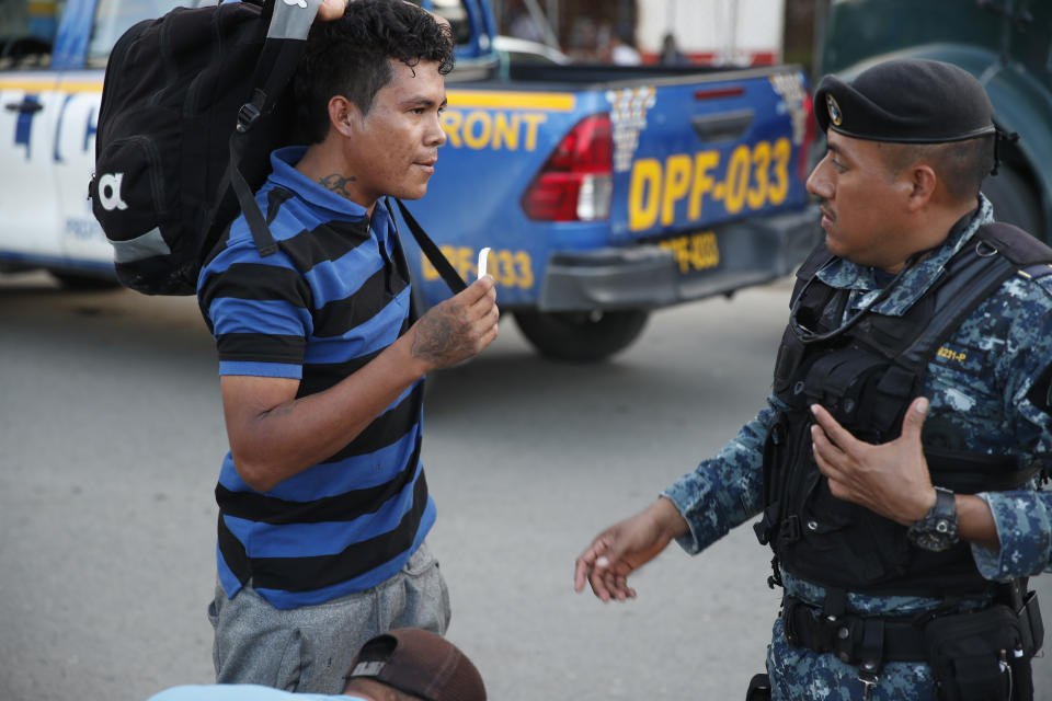 Un migrante hondureño que intenta llegar a Estados Unidos muestra su documentación ante un agente de la Policía Nacional guatemalteca en El Cinchado, Guatemala, en la frontera con Honduras, el miércoles 15 de enero de 2020. (AP Foto/Moisés Castillo)